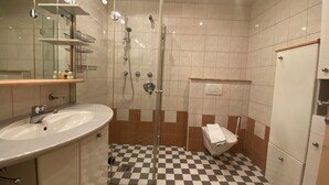 Un baño con piso a cuadros, un lavamanos, una ducha y un inodoro.
