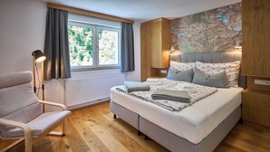 Une chambre à coucher avec un lit, une chaise, une carte accrochée au mur et une fenêtre avec des rideaux.