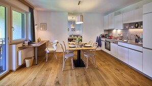 Une cuisine moderne avec un coin repas, un plancher en bois et des meubles de rangement blancs.