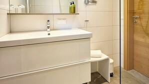 Une salle de bain moderne avec un meuble-lavabo blanc, un grand miroir et une porte en bois.