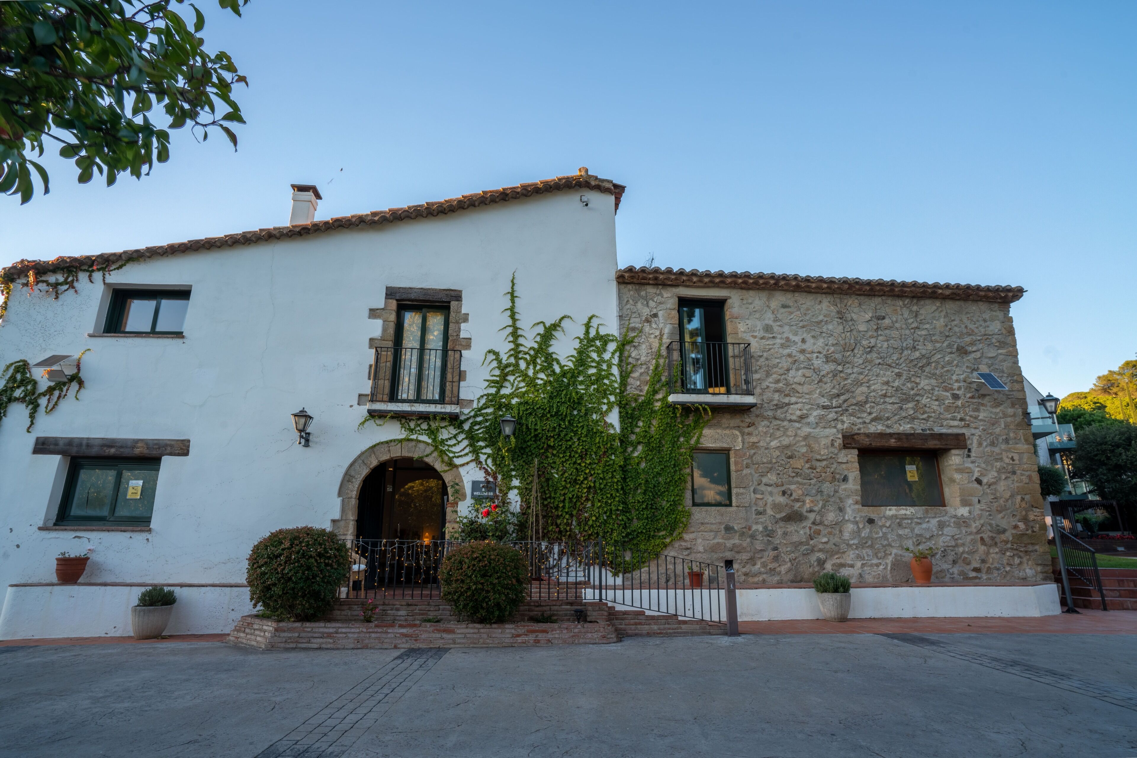 A two-story building with a white facade, stone upper section, and a central entrance with a small porch.