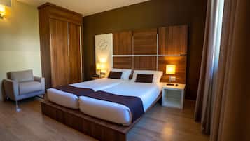 Una habitación de hotel moderna con una cama grande, un sofá, una mesita de noche y un televisor montado en la pared.