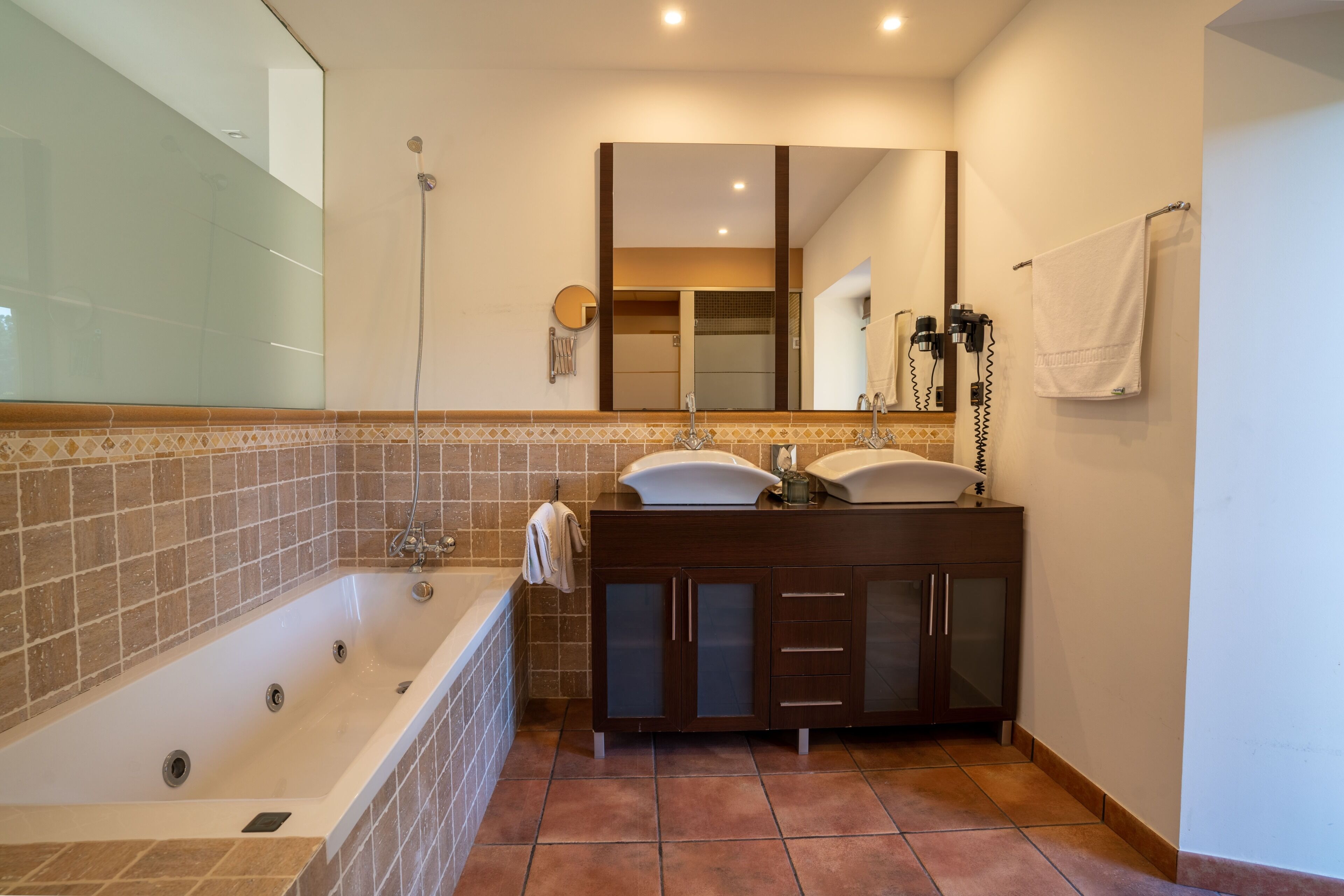 Un baño con bañera, tocador con espejo y perchero.