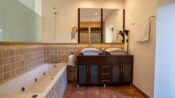 Un baño con bañera, tocador con espejo y perchero.