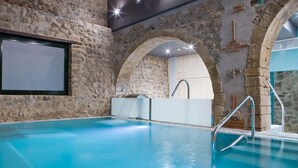 An indoor swimming pool with stone walls and a modern design. - Hotel & Spa Golden Barcelona (Vallromanes)