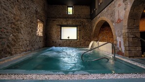 An indoor swimming pool with stone walls, a window, and a metal ladder. - Hotel & Spa Golden Barcelona (Vallromanes)
