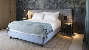 Quarto moderno com uma cama grande, parede texturizada escura e um guarda-roupa de madeira.