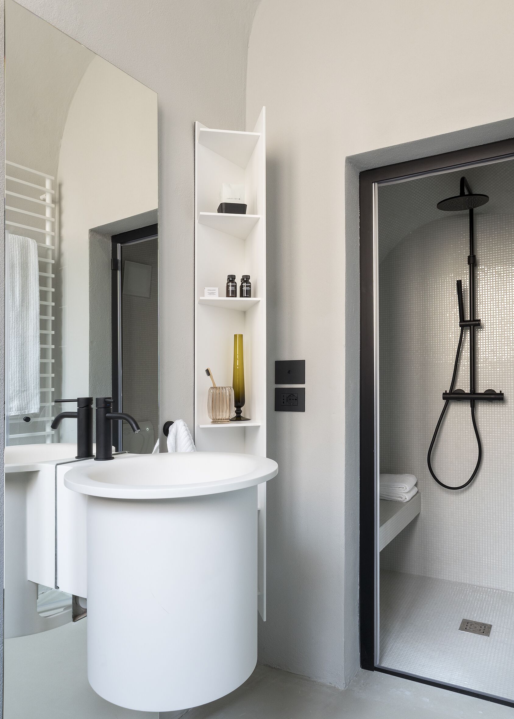 A modern bathroom with a white vanity, a large mirror, and a shower area.