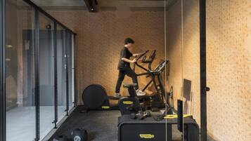 A gym with a stationary bike, weights, and a treadmill.