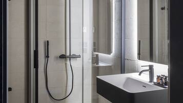 A modern bathroom with a glass-enclosed shower, a white sink, and a large mirror.