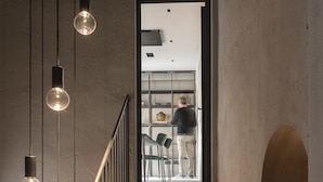 A staircase with hanging light fixtures, leading to a room with a view of a person working at a desk. - Antica Dimora Le Misure (Cervia)