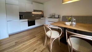 Eine moderne Küche mit weißen Schränken, einem Holztisch und zwei Korbstühlen.