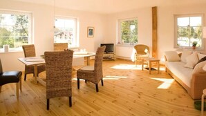 Une pièce spacieuse avec un plancher en bois, un canapé, une table à manger avec des chaises et un téléviseur.