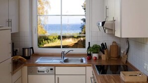 Une cuisine avec vue sur la mer, un lave-vaisselle, un évier et des plans de travail en bois.