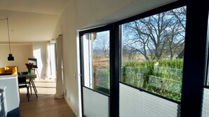 Une cuisine moderne avec un coin repas, de grandes fenêtres et une vue sur un jardin.