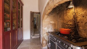 A kitchen with a stone wall, a red cabinet, and a stove.