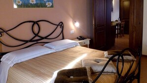 A bedroom with a bed, a nightstand, a painting of daisies, and a door leading to another room. - Apartment in Umbria with Infinity Pool Views (Bettona)