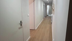 A hallway with a wooden floor, white walls, and a door on the left. - LE PETIT MONTY Gite Vue Étang 5 minutes from Puy Du Fou (Saint-Malô-du-Bois)