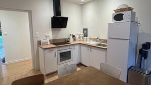A compact kitchen with a dining table, white cabinets, a microwave, and a sink. - LE PETIT MONTY Gite Vue Étang 5 minutes from Puy Du Fou (Saint-Malô-du-Bois)