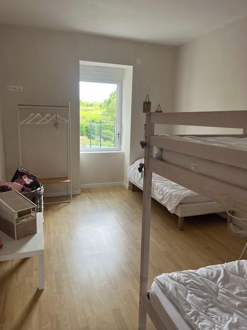 Ein Schlafzimmer mit einem Etagenbett, einem Fenster mit Blick auf Grünflächen, einem Wäscheständer und einem kleinen Tisch mit Gegenständen darauf.