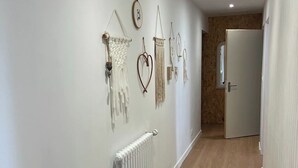 A hallway with a white radiator, wooden flooring, and wall-mounted decorations. - LE PETIT MONTY Gite Vue Étang 5 minutes from Puy Du Fou (Saint-Malô-du-Bois)