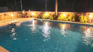 A swimming pool with clear water, surrounded by plants and illuminated by lights. - private house noko (Miyakojima)