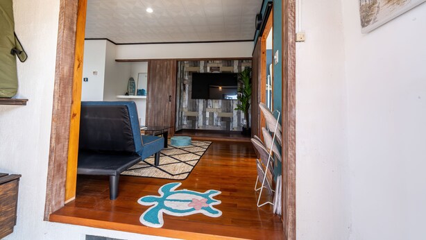 A modern living room with a sofa, a rug, and a wooden floor. - private house noko (Miyakojima)