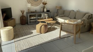 Ein modernes Wohnzimmer mit Sofa, Couchtisch, Fernseher und Dekorationselementen.