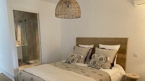 Ein Schlafzimmer mit einem Bett, einem Nachttisch, einer Pendelleuchte und einer Duschkabine.