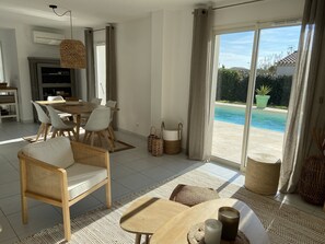 Un salon moderne avec un coin repas, une vue sur la piscine et une cuisine.