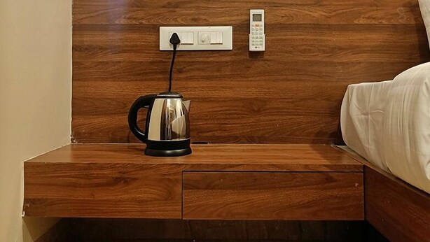 A wooden headboard with a built-in kettle and a control panel. - Hotel Essence (Vellore)