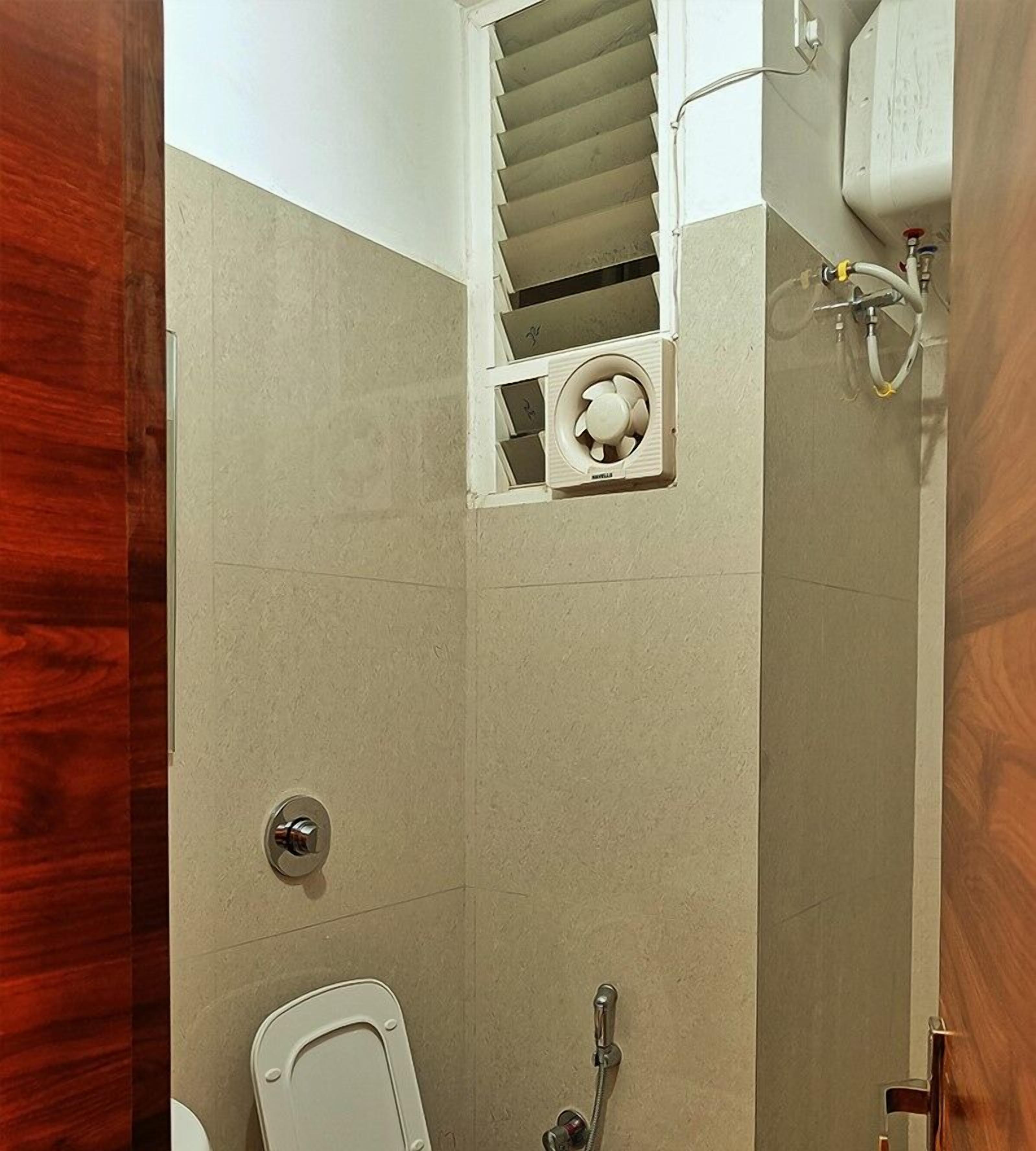 Un baño con inodoro, ducha y ventilador integrado.