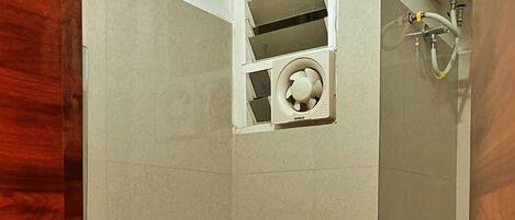 Un baño con inodoro, ducha y ventilador integrado.