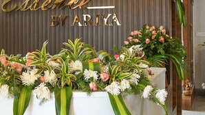 A reception area with a wooden ceiling, three hanging pendant lights, a floral arrangement, and a sign that reads "Ernesto By Aria". - Hotel Essence (Vellore)