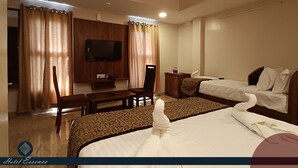 A hotel room with a bed, a desk, a chair, a television, and curtains.