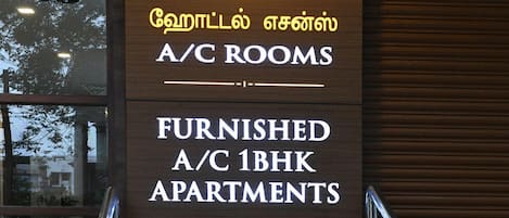 A sign for A/C rooms, furnished A/C 1BHK apartments, and a mini A/C party hall.