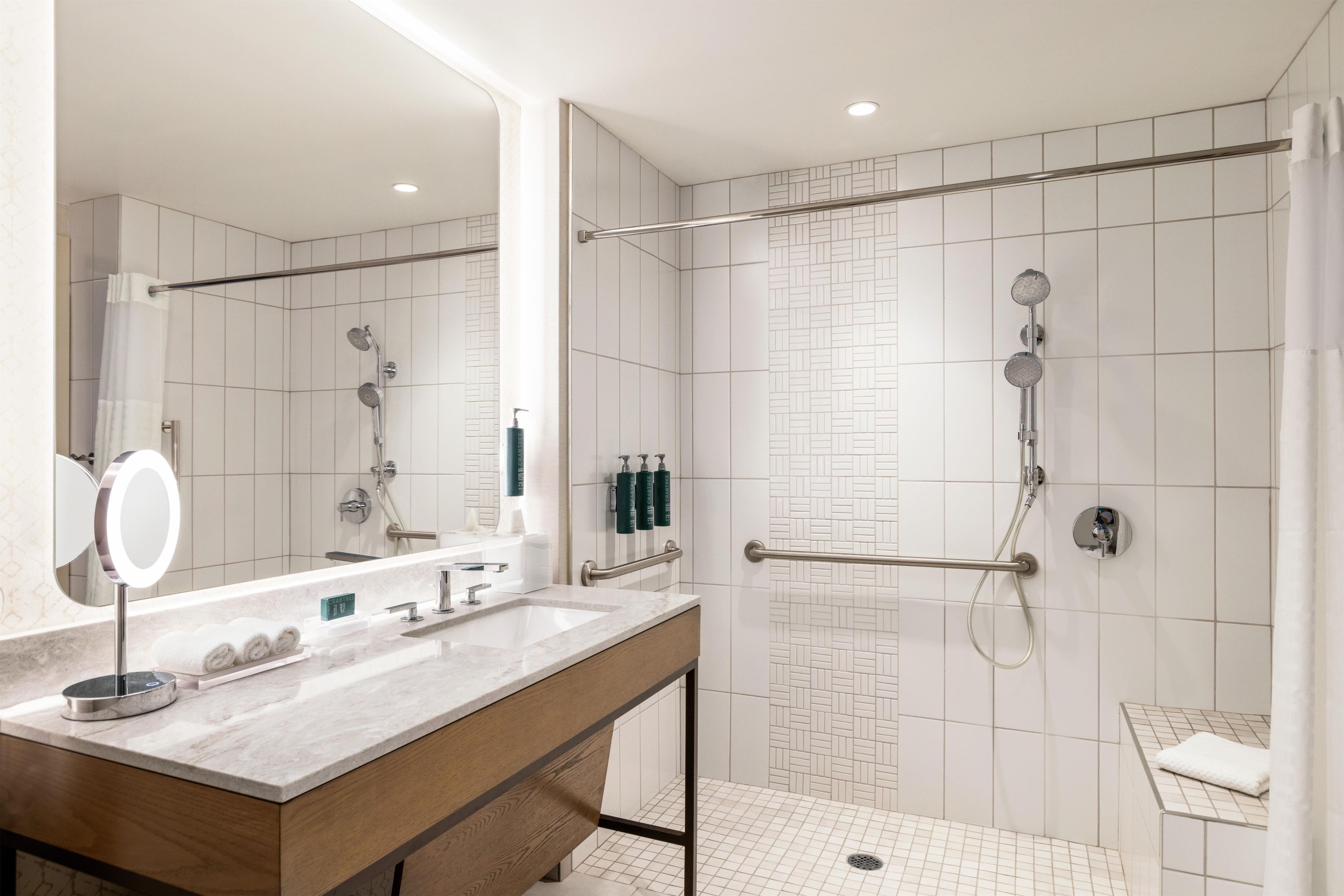 Une salle de bain moderne équipée d’une douche, d’un meuble-lavabo avec miroir et de toilettes.