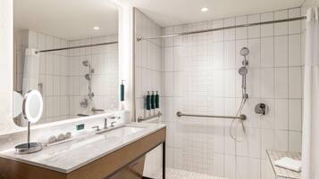 Une salle de bain moderne équipée d’une douche, d’un meuble-lavabo avec miroir et de toilettes.