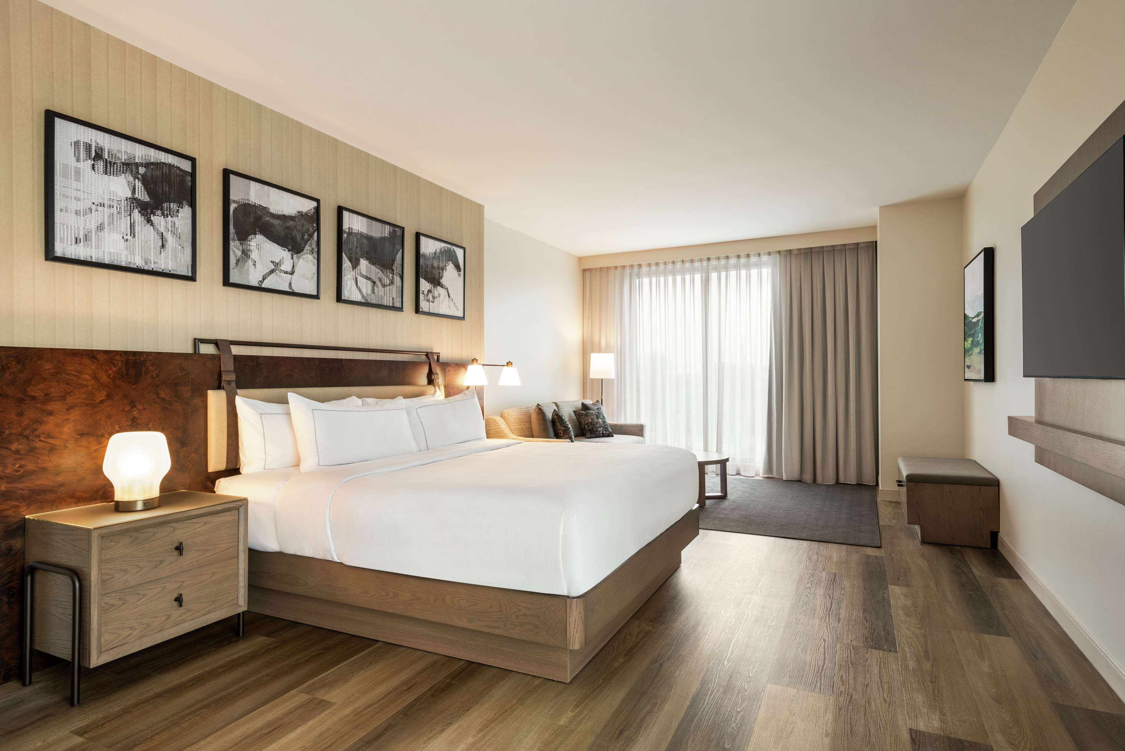 Une chambre d’hôtel dotée d’un grand lit, d’une tête de lit en bois, de tables de chevet et d’œuvres d’art accrochées au mur.