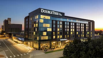 Een modern DoubleTree hotel met een glazen gevel, een terras en een helder uitzicht over de omliggende stad.