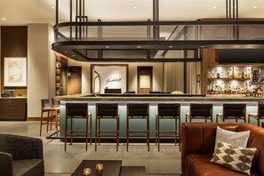Een moderne bar met een centraal bar eiland, barstoelen en een zithoek met een bank en stoelen.