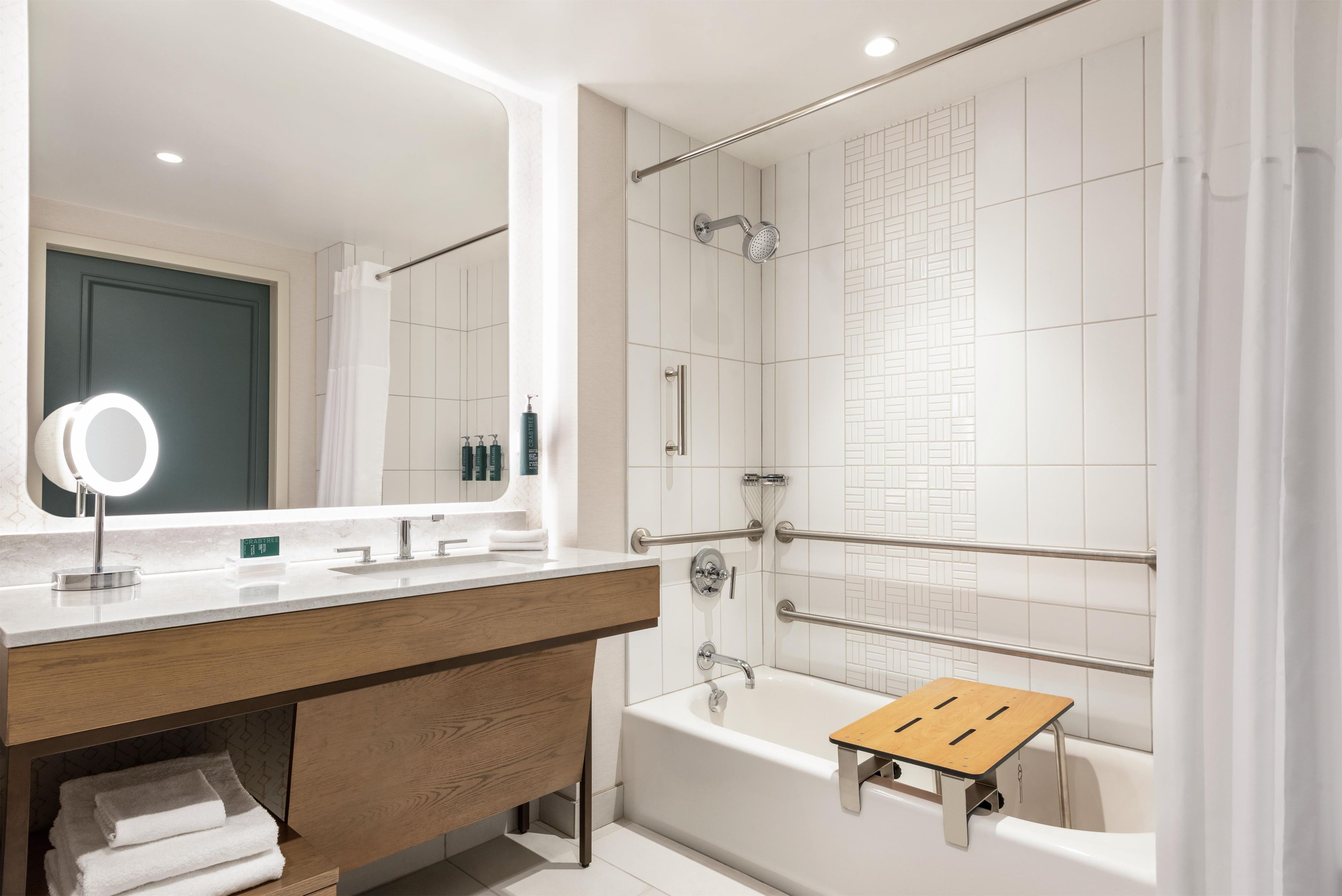 A modern bathroom with a vanity, a large mirror, a bathtub, and a shower area.