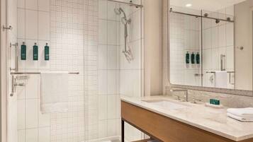 A modern bathroom with a glass-enclosed shower, a large mirror, and a vanity with a marble countertop.