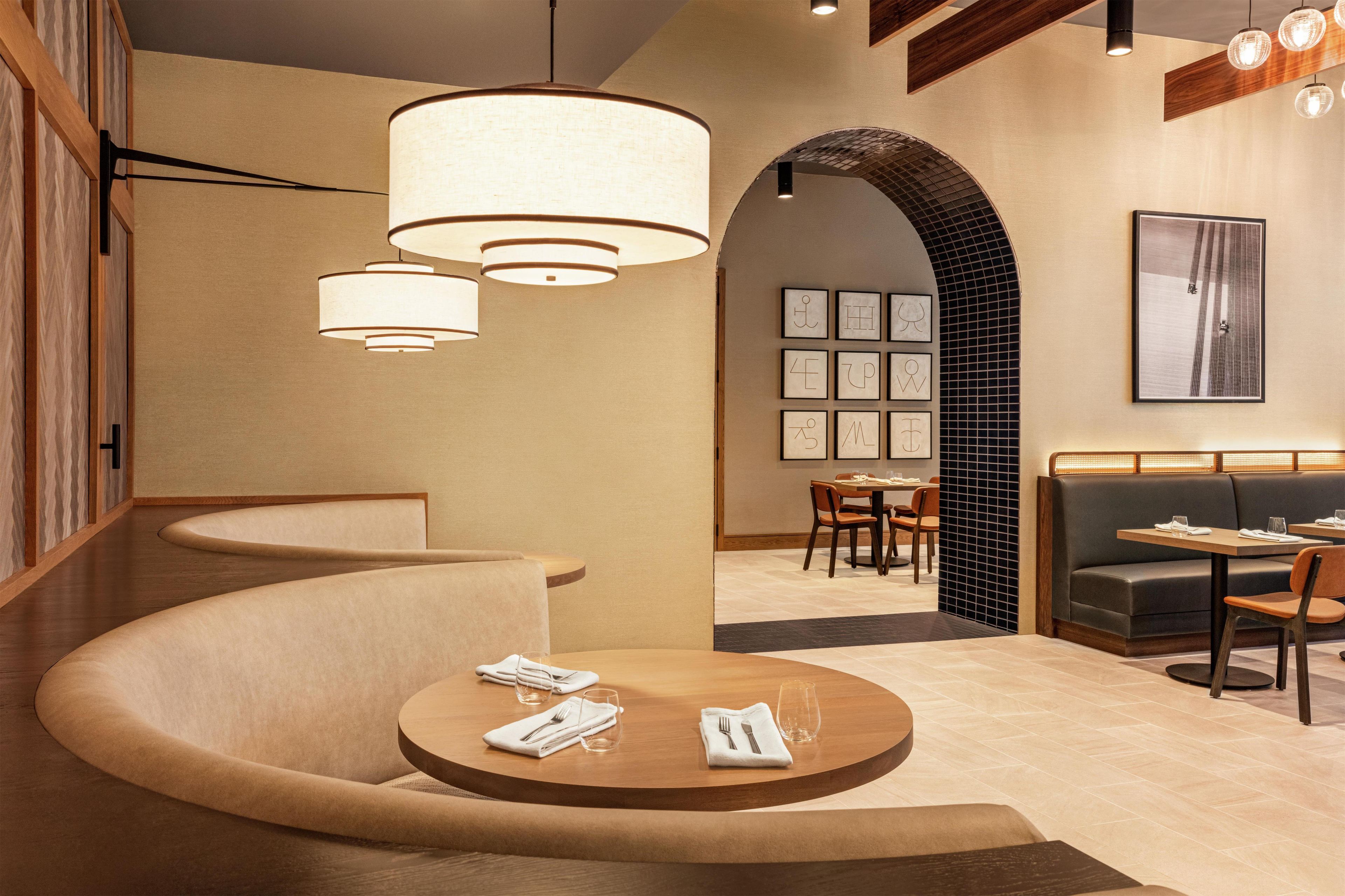 A modern interior with a curved seating area, a round table with a glass, and a wall with framed pictures.