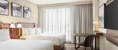 Ein Hotelzimmer mit zwei Betten, einem Schreibtisch, einem Stuhl und einem Fernseher.