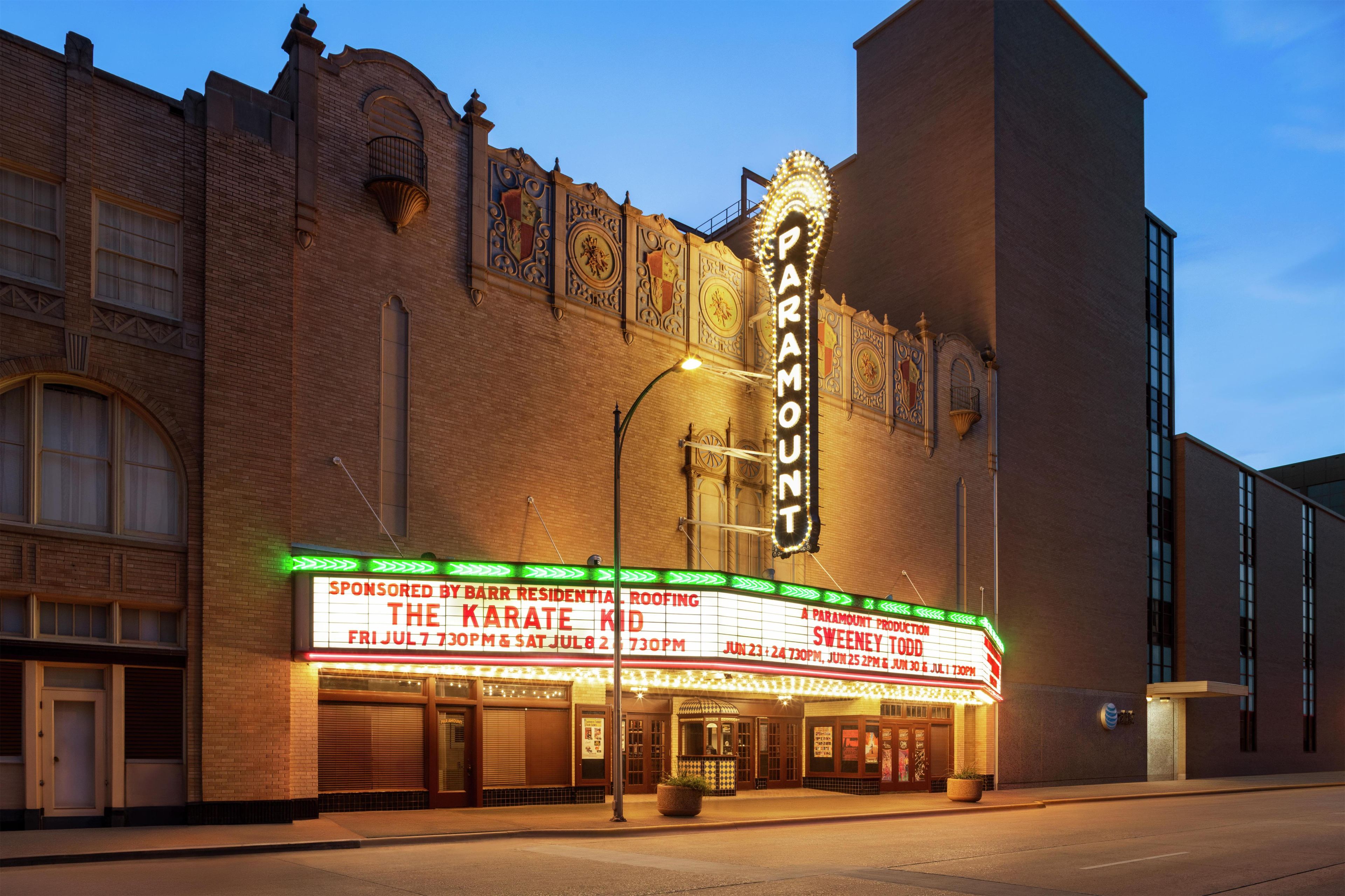 A brick theater with a marquee advertising 'The Karate Kid' and 'Sweeney Todd' shows.