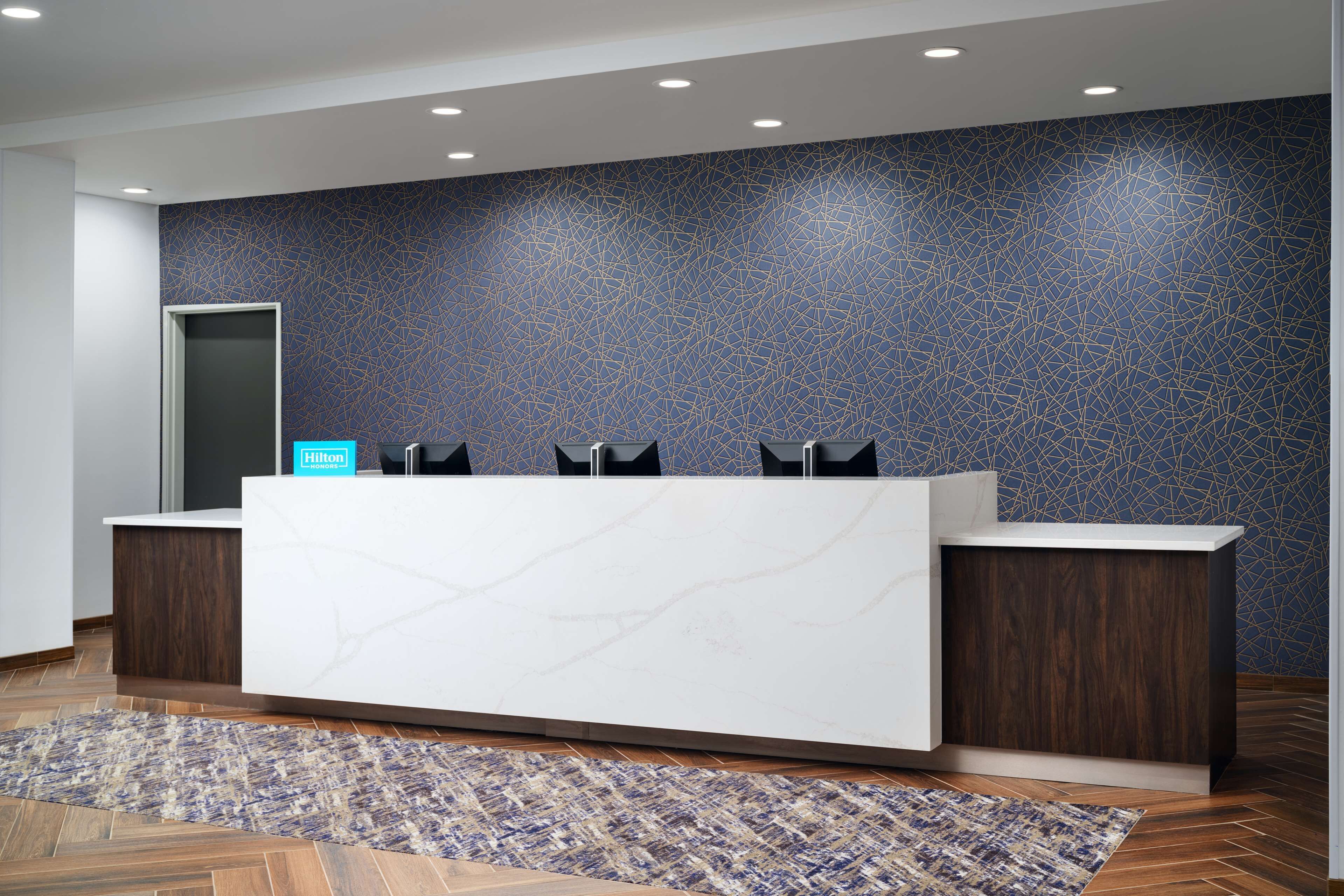 A reception desk with a modern design, a patterned wall, and a wooden floor.
