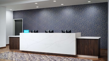 A reception desk with a modern design, a patterned wall, and a wooden floor.
