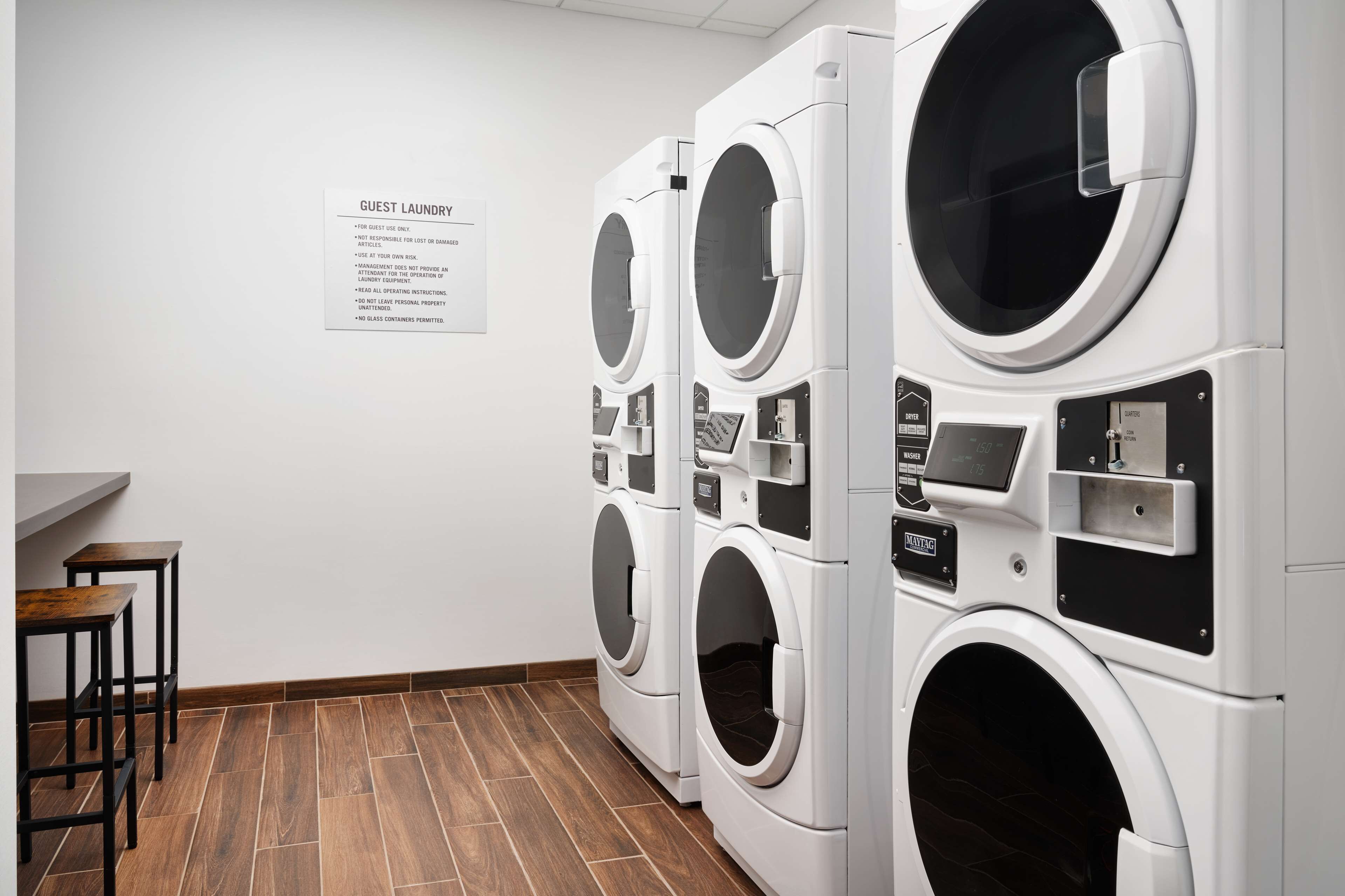 Un espace buanderie à la disposition des clients, équipé de plusieurs machines à laver et d’un panneau indiquant les consignes d’utilisation.
