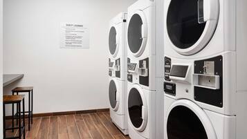 Un espace buanderie à la disposition des clients, équipé de plusieurs machines à laver et d’un panneau indiquant les consignes d’utilisation.